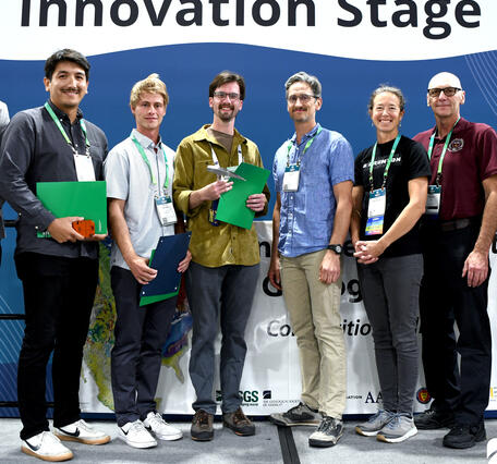 Eight people standing shoulder to shoulder in front of a banner reading Innovation Stage.