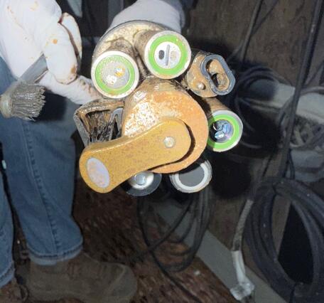 A gloved hand holds up cylindrical sensors attached to a central body with a wiper in the middle.