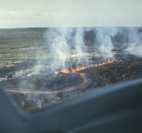 Color photograph of a line of erupting vents and a channelized lava flow