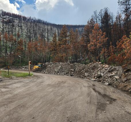 heavy equipment next to a pile of debris on the side of the road