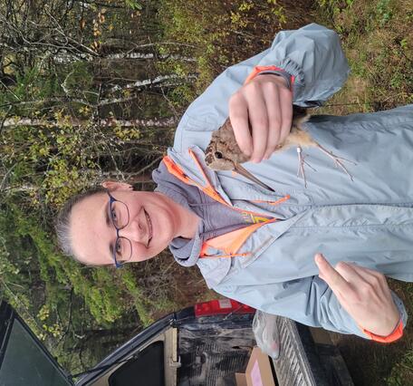 Sarah Clements staff profile picture. Woman in blue jacket holding bird.