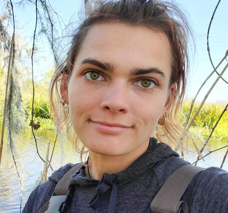 McKenzie Smith wearing waders on a sunny day near a wetland