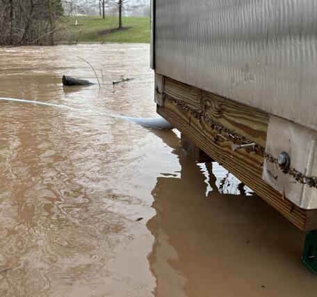 A brown flooded river flows just underneath a streamgage platform
