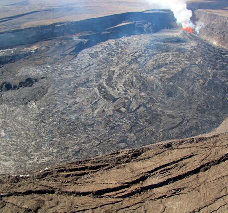Color photograph of caldera with fresh lava flows and active eruption