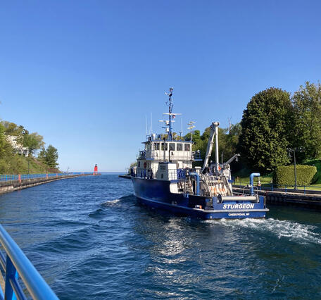 A research vessel moves through a channel toward Lake Michigan
