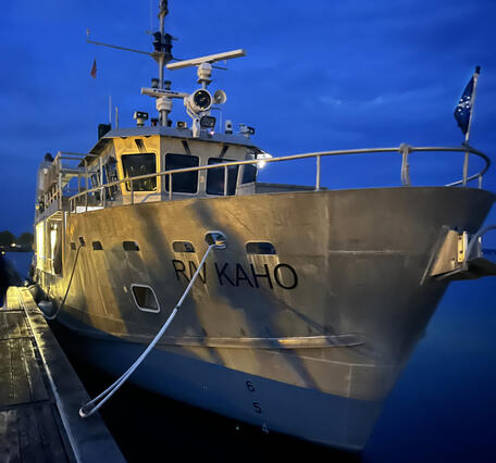 Bow of a large research vessel docked at night. R/V Kaho on the starboard side of the bow
