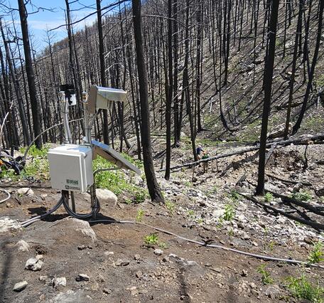 Equipment on a hillslope that is covered with rocks and burned trees