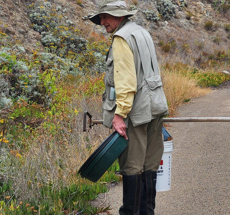 Scientist Charles Drost carries gear while walking along a road on San Clemente Island during a monitoring study