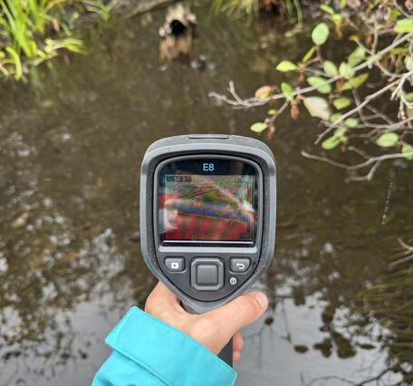 A close up of a handheld device pointed at a river.