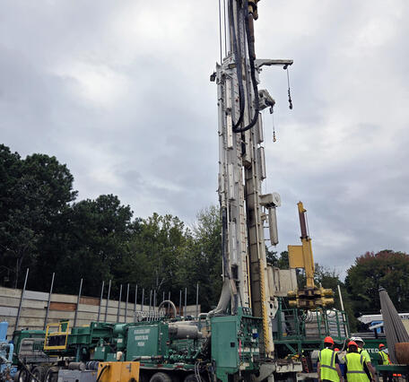 A drilling rig at the site of the James River Extensometer. Several individuals in hardhats and safety vests tour the rig.