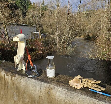 Sediment sampler and bottle on bridge railing