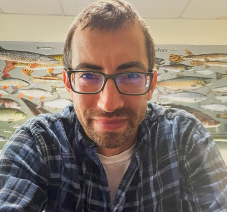 Person in an office leaning toward camera with fish mural in the background