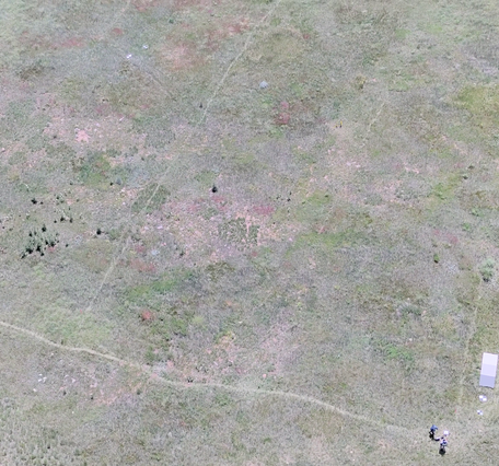 Aerial photo looking down at a field with drone operator and reference objects used for calibration of payload instruments