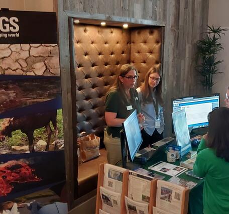 Two USGS scientists behind a booth talking to two people on the other side of the booth