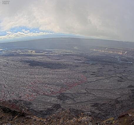 Color photograph of lava fountain within crater in the background with lava flows in the foreground