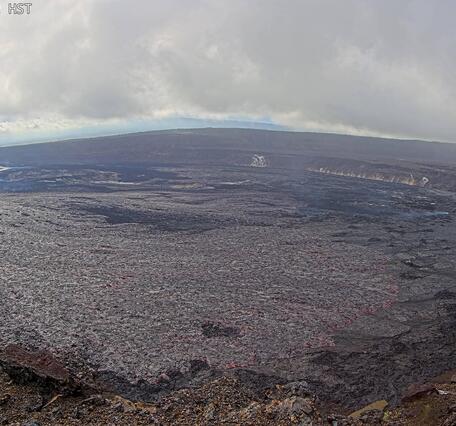 Color photograph of lava fountain and lava flow within volcanic crater