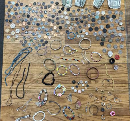 Coins, hair ties, and assorted jewelry laid out on a wooden table