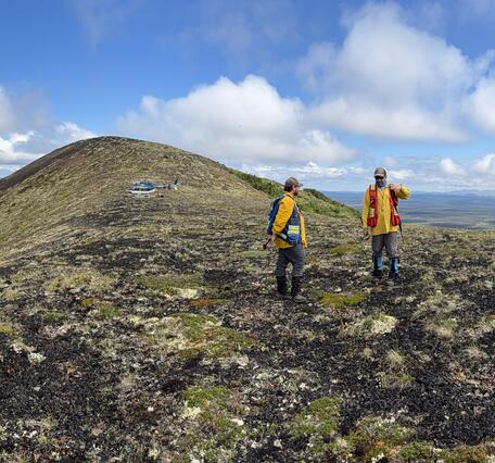 Two people in orange jackets standing on an alpine ridge