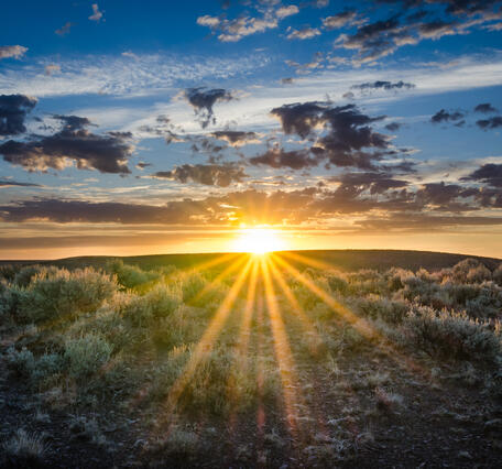 partly cloudy subset over a flat sagebrush landscape
