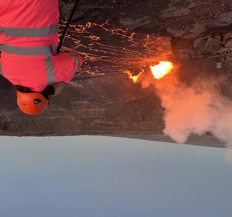 Geologist looking into crater where orange lava fountains are erupting
