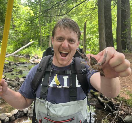 Man in waders holding a crayfish in the foreset