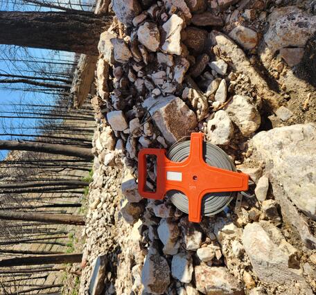 tape measure sit on top of a deposit of rocks and mud