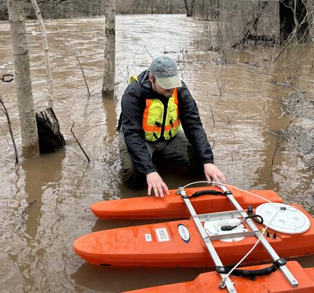 hydrologic technician prepares to measure streamflow on flooded creek with ADCP
