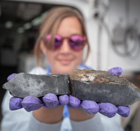 A person in sunglasses holds up rocks