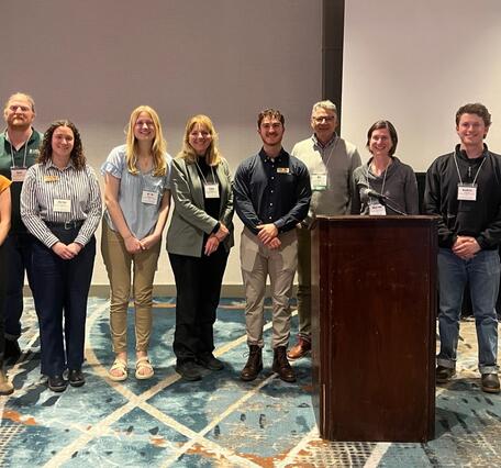 Eleven people at a conference standing in a line smiling for the camera
