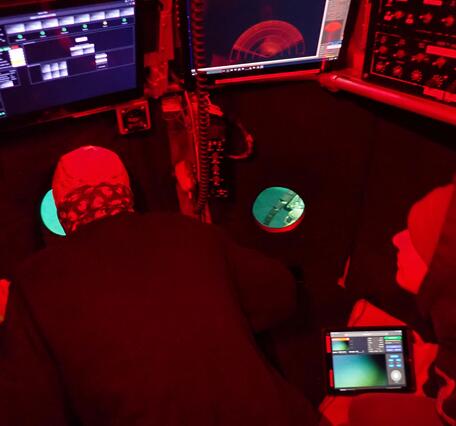 Red light glows over a pilot and the inside of the Alvin submersible