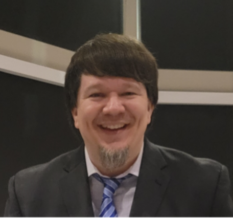 brunette smiling man with some facial hair and a suit and tie