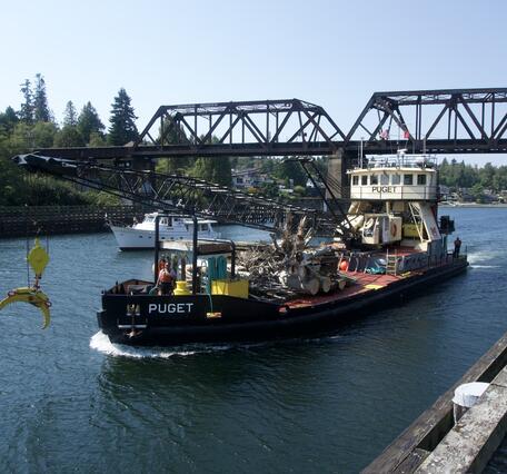 boat with onboard crane goes through the blue canal waterway on a clear sky day