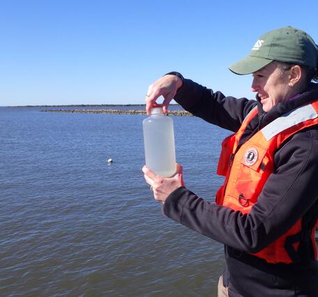 A scientist hold a bottle of water containing a surface water sample to estimate phytoplankton biomass
