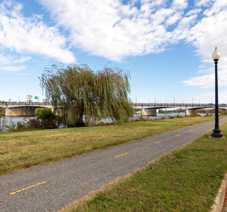A bike path runs parallel to a road with green grass on either side