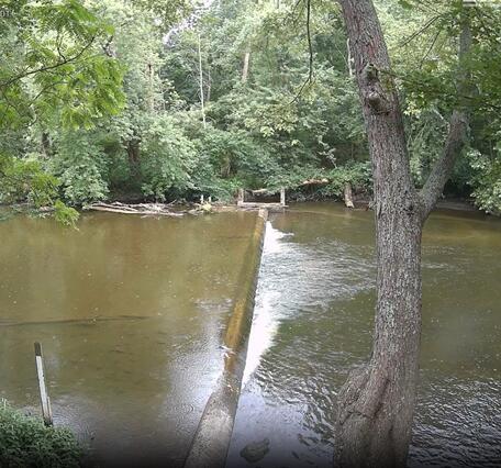 Looking across a river along the concrete weir 