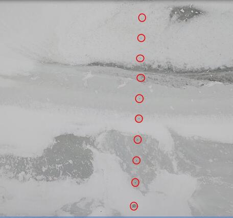 Looking down on the frozen Delaware River with red highlights shoeing the measurement sites in the ice