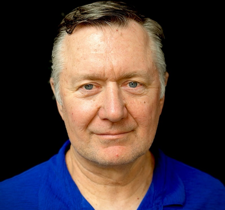 man with blue eyes wearing a blue shirt with a black background
