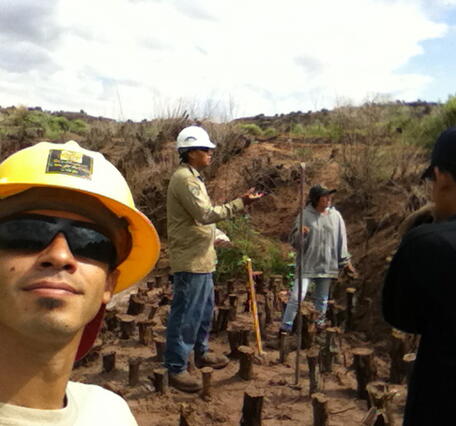 A man in safety gear takes a picture of himself with his crew.