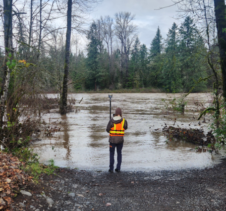 Scientist stands at the water's edge of the flooded boat ramp.