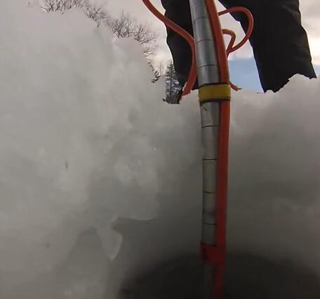 Looking at a person's legs as they lower a scientific probe down through a hole in the ice to the water below