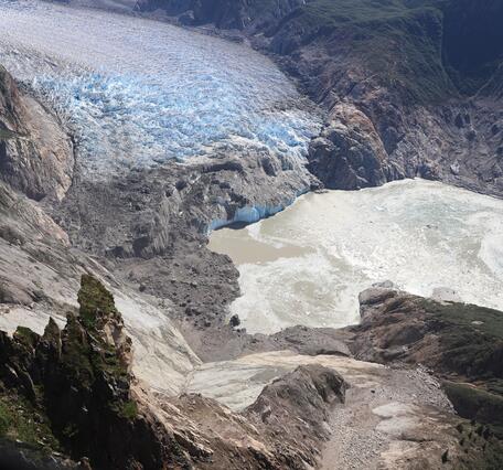 Aerial photo looking down a mountainside with the landslide in the foreground and glacier in the background