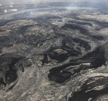 Black and light gray lava flows cover a volcanic crater floor