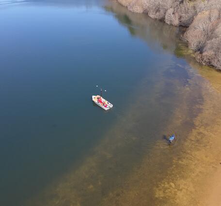 aerial view of small boat near shoreline on pond