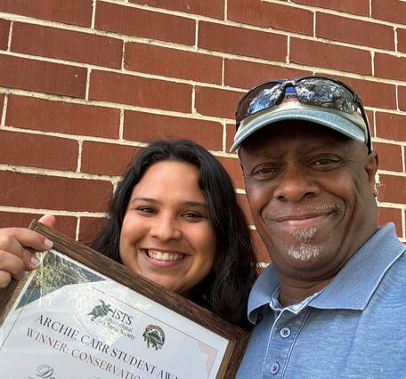 Two people are holding an award
