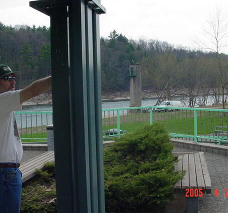 A man pointing out how high the river got on the Beach Office and showing the gage house in the background