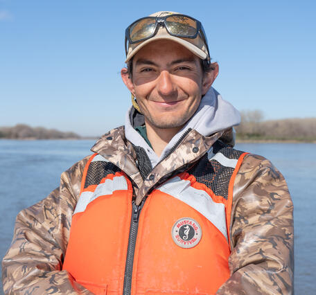 profile picture of man smiling with orange life jacket vest and hat