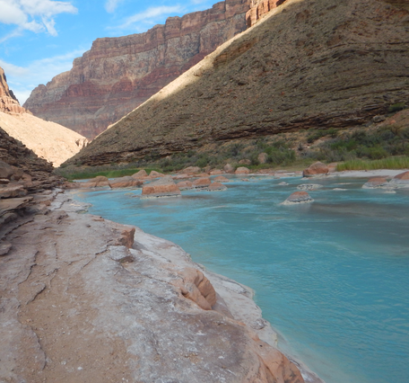 The light blue Little Colorado River flows through a red rock canyon