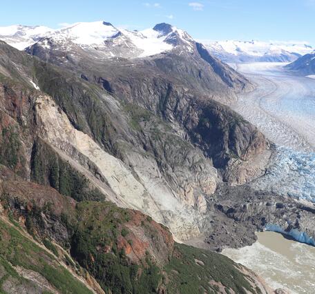 Photo of mountainside with landslide in the center and glacier to the right