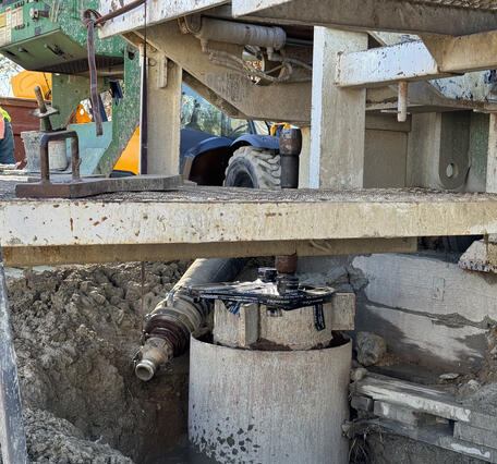 Completed extensometer borehole. Multiple nested pipes protrude from the surface and the drill rig is still in place above.