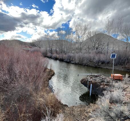 East Walker River flowing past bare trees under cloudy sky  with new streamflow monitoring equipment in foreground.